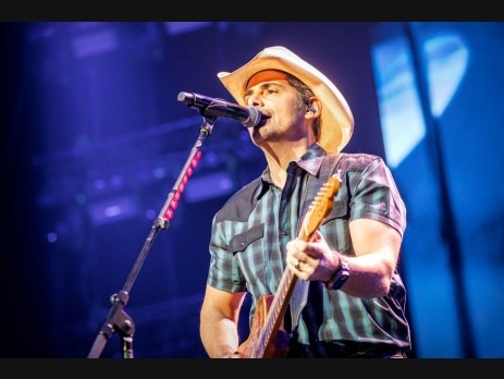 Brad Paisley singing and playing electric guitar on stage in a cowboy hat