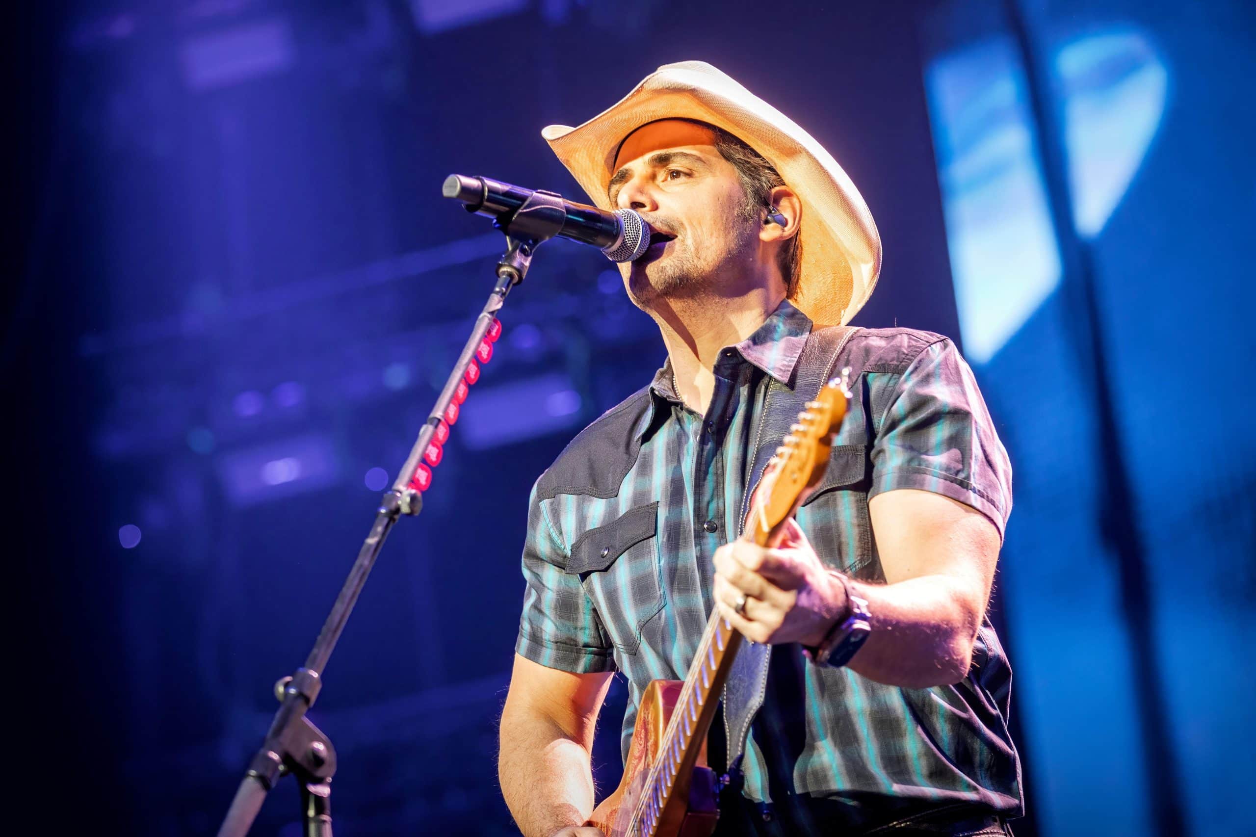 Brad Paisley singing and playing electric guitar on stage in a cowboy hat