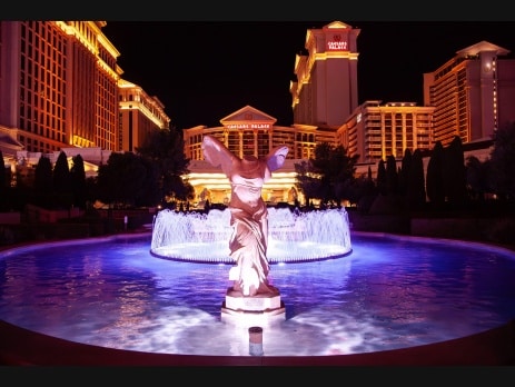 Caesars Palace lit at night behind the winged Victory statue and fountain on the Las Vegas Strip
