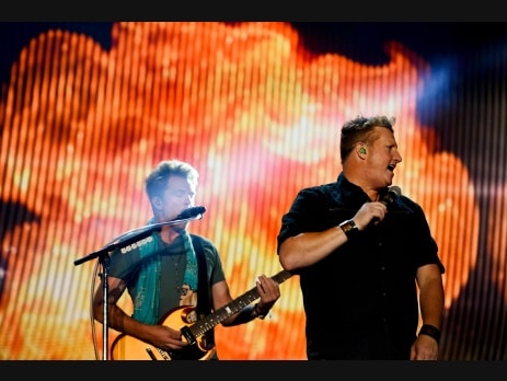 Rascal Flatts performing live, singing and playing guitar on a brightly lit stage