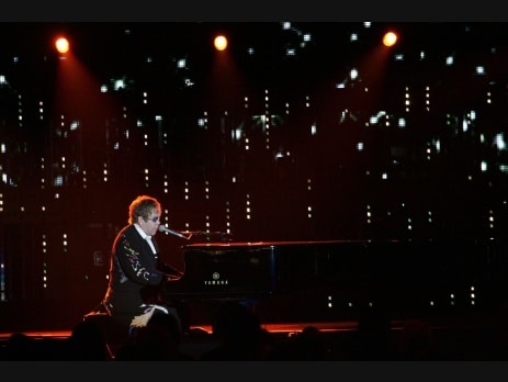 Elton John performs at the piano during a concert