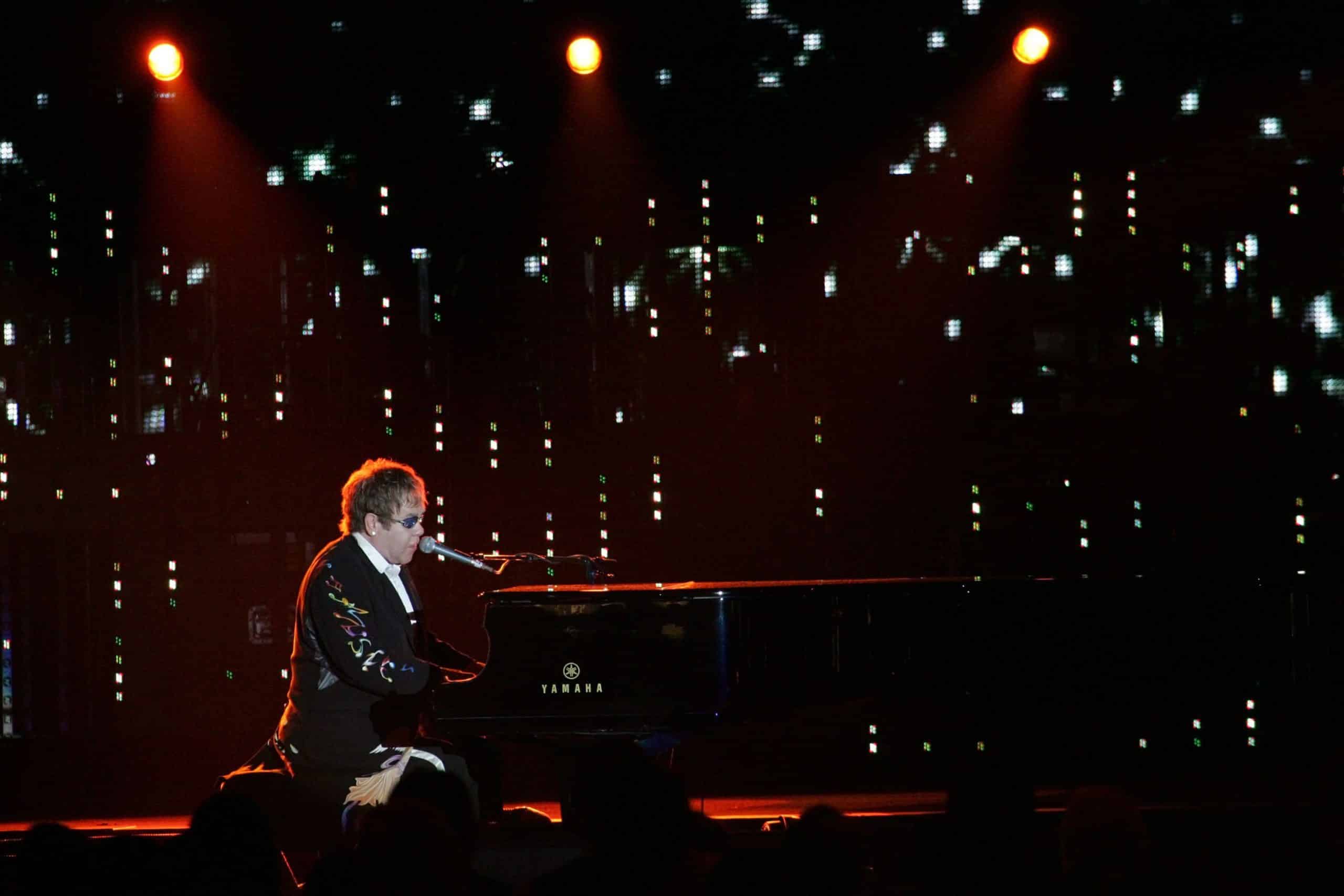 Elton John performs at the piano during a concert