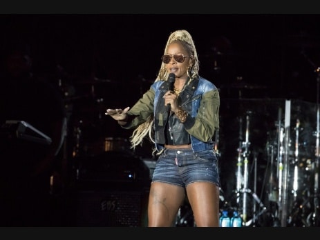 Mary J Blige performing live on stage holding a microphone