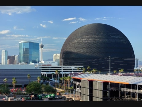 Sphere at Las Vegas in daylight with the Strip skyline, including the Stratosphere Tower, visible behind it