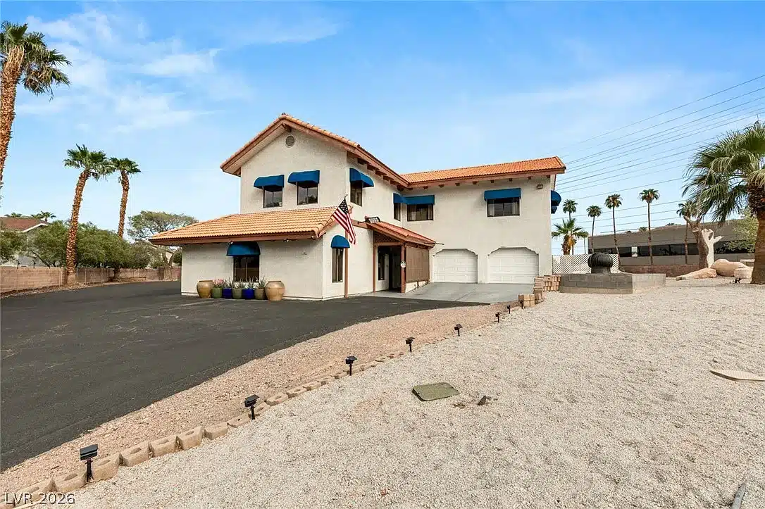 Two-story stucco house with a red tile roof, blue window awnings and a two-car garage in Las Vegas